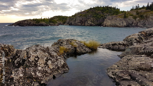 Scenic untouched landscape of a Lake Superior bay in the Pukaskwa Nationalpark. Photographed from a low angle showing a high positioned shallow pond reflecting the sunlight