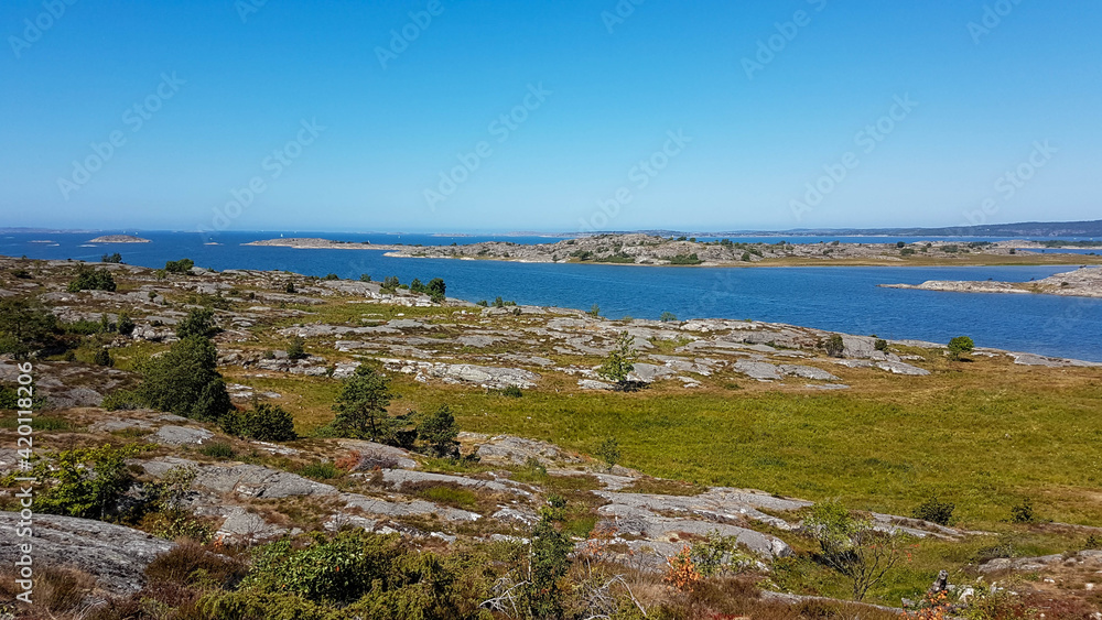 Far scenic landscape showing a wide rocky grassland streaked by a calm bay