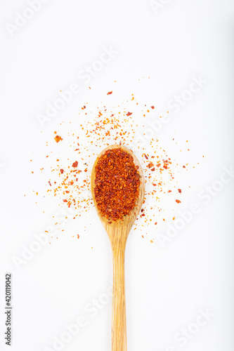 Red chili pepper in wooden spoon on white background.