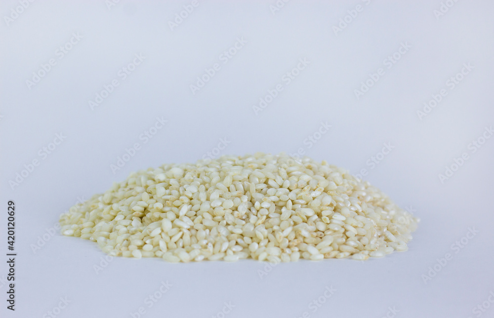 Uncooked arborio rice. Risotto rice on white background. Pile of