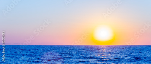 Fototapeta Naklejka Na Ścianę i Meble -  Orange sunset over sea. Bright sun over the sea horizon. Concept: vacation and relax
