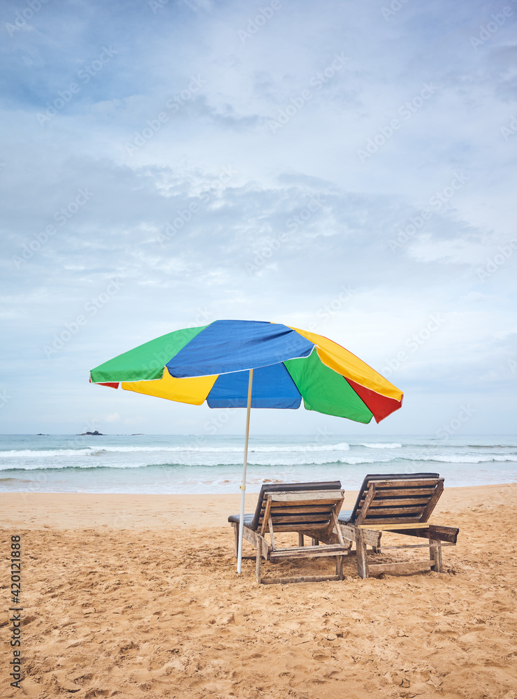 Umbrella with two sunbeds on an empty tropical beach, Sri Lanka.
