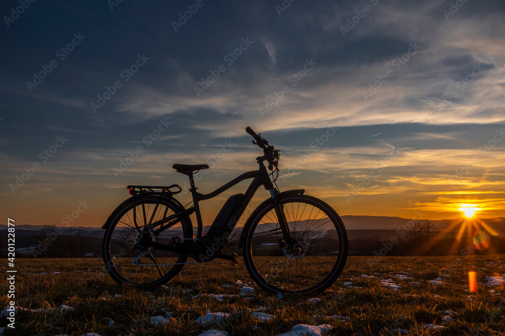 Black and gray electric bicycle in sunrise morning time on frosty field
