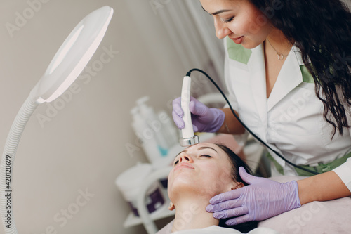 Close up of head woman receiving electroporation phonophoresis facial therapy at beauty spa salon. photo