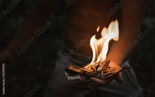 Young man with a burning match in the dark fire