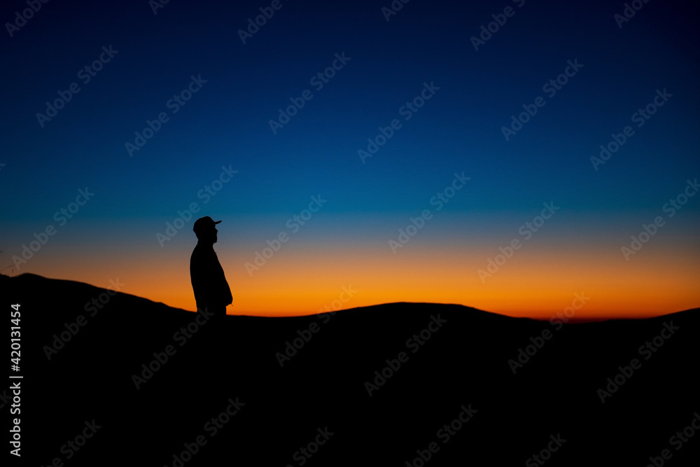 Silhouette of man standing on high mountains during sunset