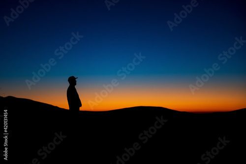 Silhouette of man standing on high mountains during sunset