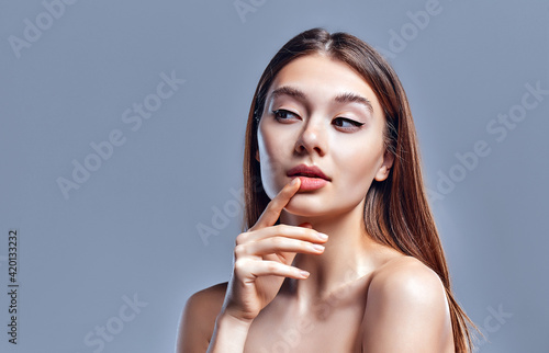 Beautiful young woman with clean perfect skin. Portrait of beauty model with natural nude makeup. Spa  skin care and wellness. Close up  gray background  copyspace.