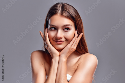 Beautiful young woman with clean perfect skin. Portrait of beauty model with natural nude makeup. Spa, skin care and wellness. Close up, gray background, copyspace.