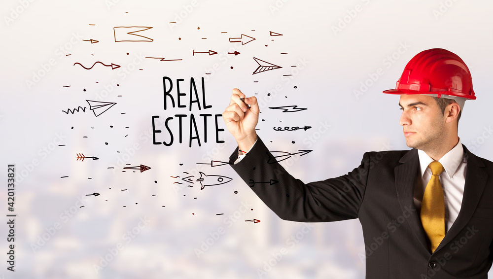 Young businessman with helmet drawing sale sign Young businessman with helmet drawing sale sign