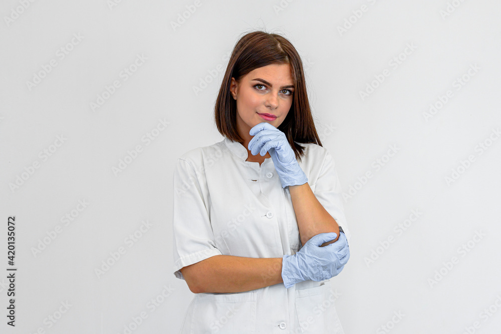 Portrait of confident young woman doctor. She is wearing white uniform and blue protective gloves. Portrait of confident young woman doctor. She is wearing white uniform and blue protective gloves.
