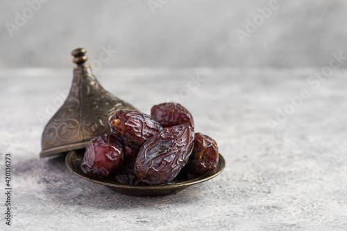 HURMA, Dates. Dried dates fruit with wooden plate on white background. Popular fruit of Ramadan. photo