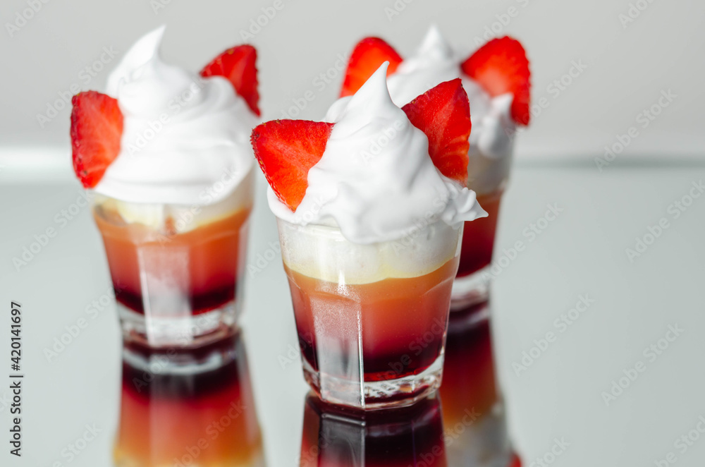 Colorful layered shots of drinks based on vodka, grenadine and orange juice decorated with whipped cream and pieces of strawberry in the shape of bunny ears Colorful layered shots of drinks based on vodka, grenadine and orange juice decorated with whipped cream and pieces of strawberry in the shape of bunny ears