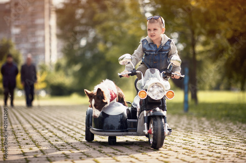  boy standing on motorcycle toy with sidecar and dog in it © luckybusiness
