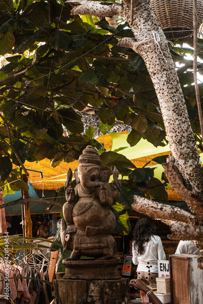 Posąg statua hinduskiego Boga Ganesha, na jasnym roślinnym tle. - obrazy, fototapety, plakaty 