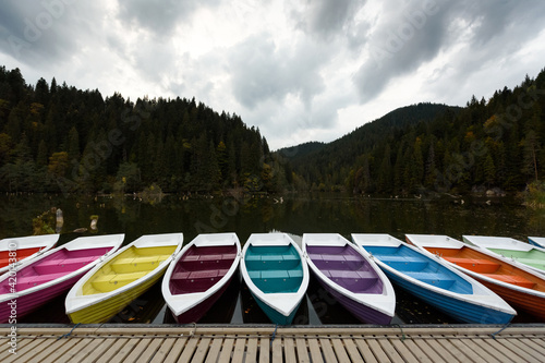 Colorful boats near the pier on the Red Lake in Transylvania, Romania in autumn. Travel across Europe. The area of ​​the Romanian Carpathians.