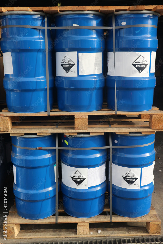 Drums containing corrosive hazardous waste drums are stacked on pallets