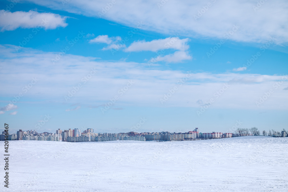 Landscape of urban high-rise buildings on background of blue sky and white snow