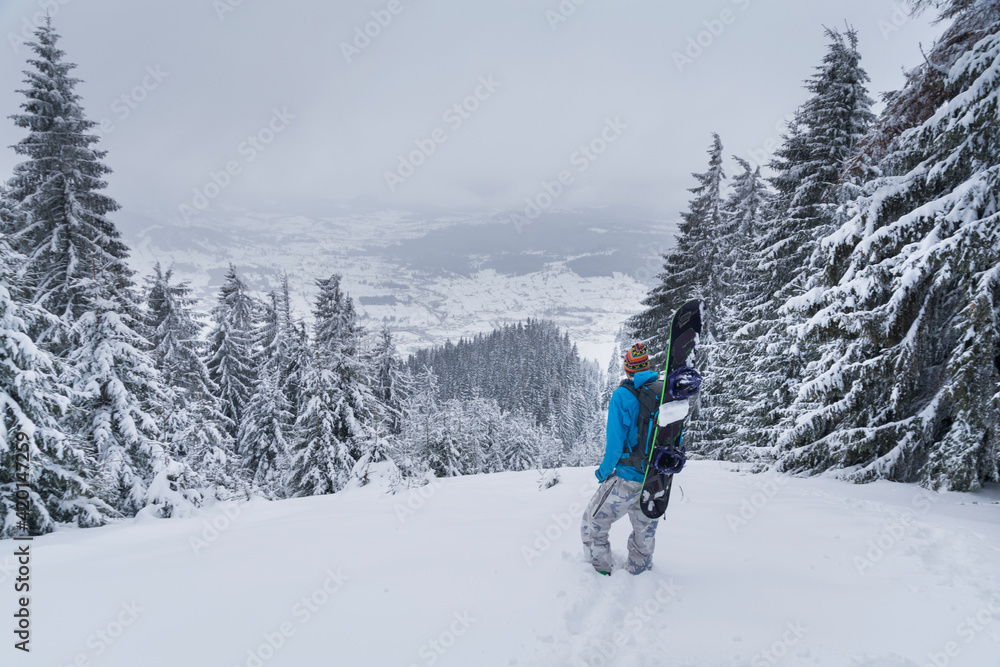 Snowboarder in mountains carrying the board on the backpack