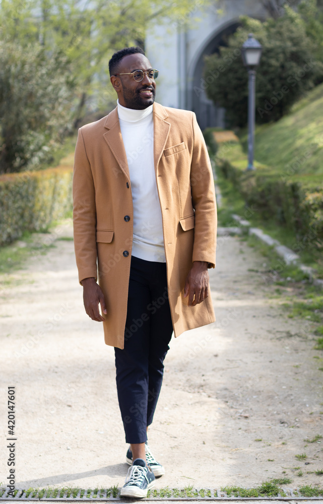 Black man walking with glasses, well dressed. No looking. In a park Black man walking with glasses, well dressed. No looking. In a park