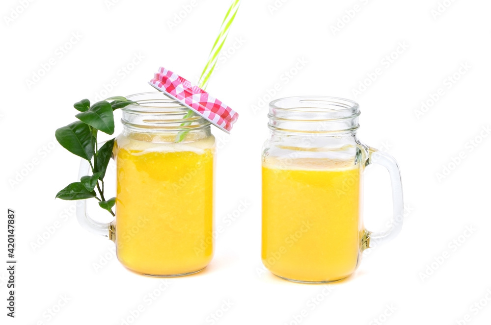 Orange juice and green leaves isolated on a white background.Two glasses of orange juice and drinking straw. Healthy food. Orange juice and green leaves isolated on a white background.Two glasses of orange juice and drinking straw. Healthy food.
