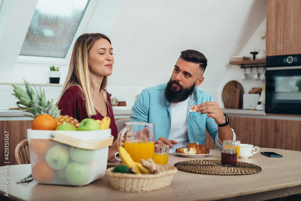 Young couple having breakfast in the kitchen at home