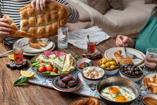 Delicious rich Traditional Turkish breakfast include tomatoes, cucumbers, cheese, butter, eggs, honey, bread, bagels, olives and tea cups. Ramadan Suhoor aka Sahur (morning meal before fasting).  photo