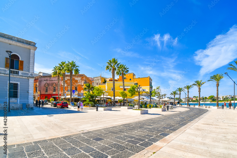 A colorful outdoor cafe restaurant at the waterfront harbor and port promenade of the coastal city of Brindisi, Italy, in the Puglia region.