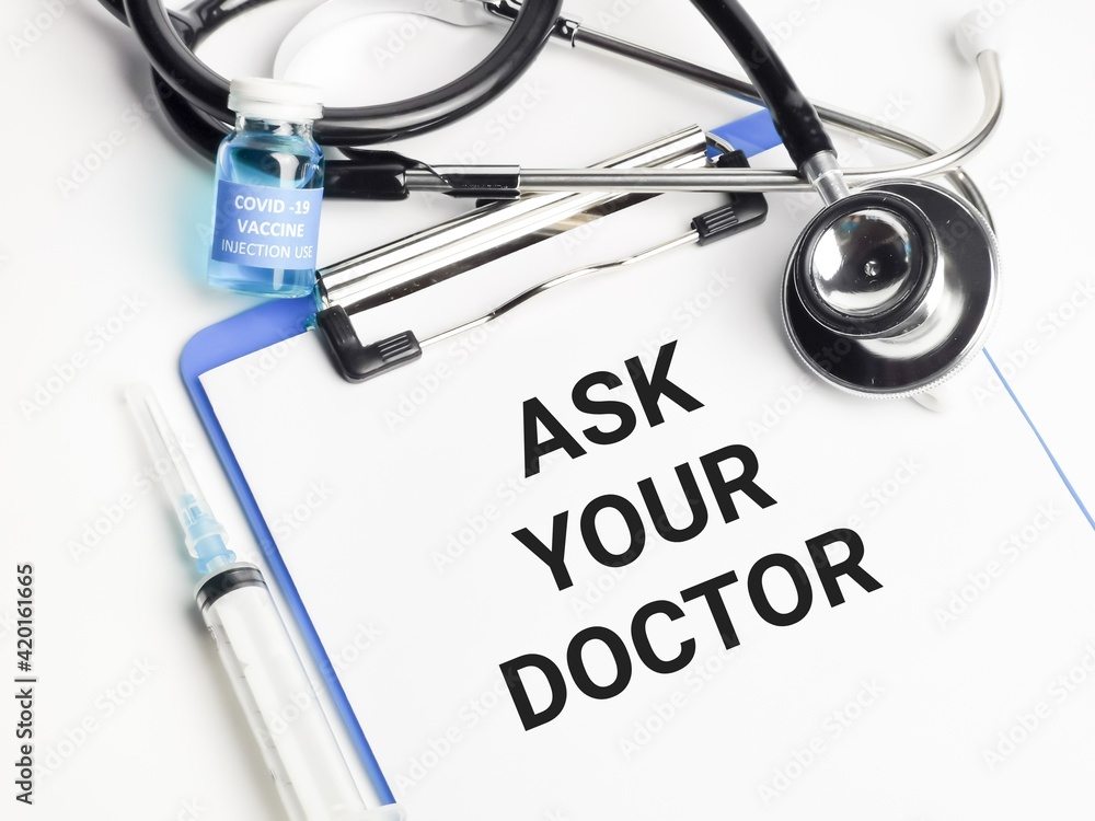 Phrase ASK YOUR DOCTOR written on paper clipboard with stethoscope,styringe and covid 19 vaccine. Phrase ASK YOUR DOCTOR written on paper clipboard with stethoscope,styringe and covid 19 vaccine.