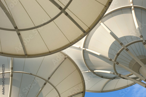 Low angle view huge canopies tensile membrane structure against the sunny blue sky.