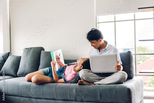 Asian man relaxing using laptop computer working and video conference meeting chat with girl daughter use laptop computer learning with online education e-learning system at home.work from home