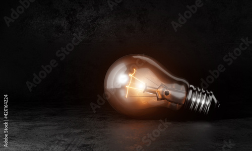 Light bulb with orange warm white light in dark room background and copy space. Conceptual and Creative invention symbol concept. 3D illustration rendering graphic