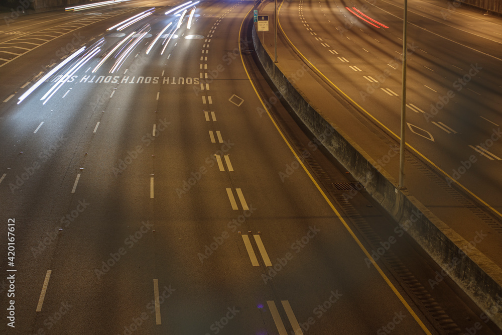 Traffic on the interstate through a blurred fence and light trails Traffic on the interstate through a blurred fence and light trails