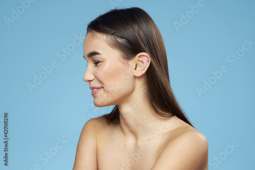 Woman with naked shoulders long hair cosmetics attractive look blue background