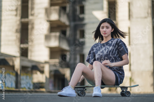 Asian women on skates board outdoors In the city on beautiful . Happy young women play surfskate at park Street