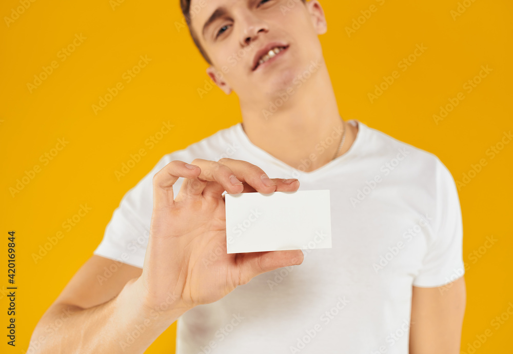 man in white t-shirt showing business card on yellow background cropped view man in white t-shirt showing business card on yellow background cropped view