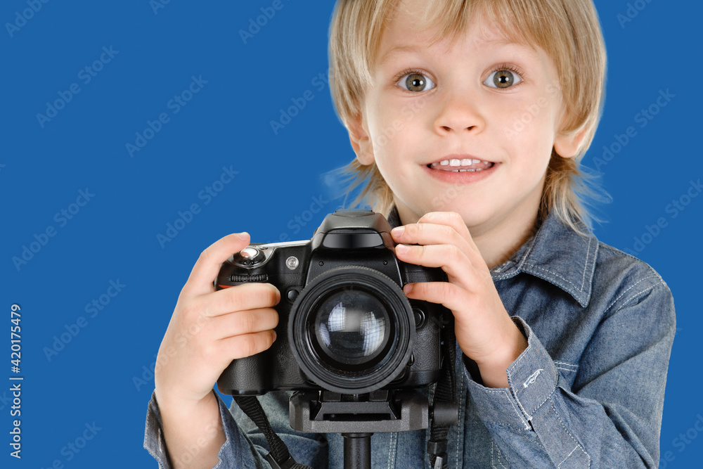 Portrait of cute little smiling boy with camera on tripod
