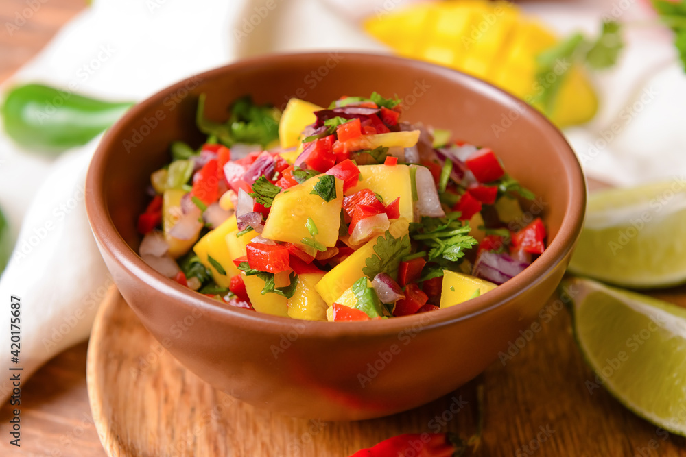 Bowl with fresh mango salsa on wooden background, closeup Bowl with fresh mango salsa on wooden background, closeup