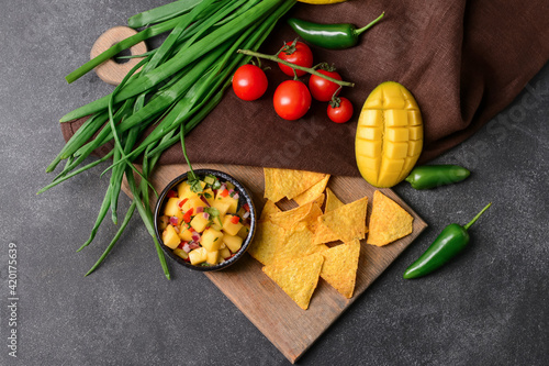 Composition with fresh mango salsa and nachos on dark background