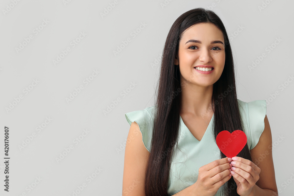 Beautiful young woman with red heart on light background Beautiful young woman with red heart on light background