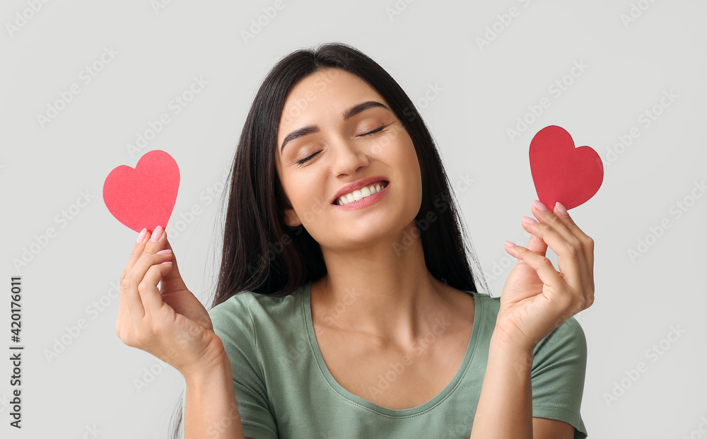 Beautiful young woman with red hearts on light background Beautiful young woman with red hearts on light background