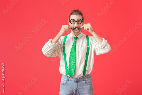 Young man in funny disguise on color background. April Fools Day celebration © Pixel-Shot