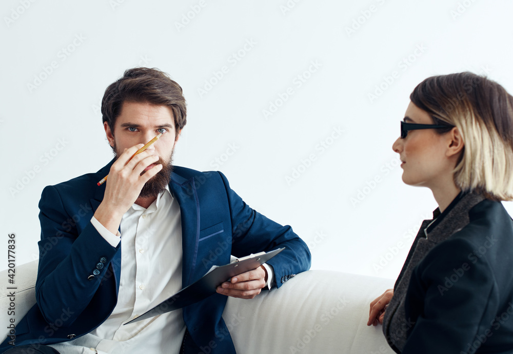 Business man with documents explains something to a young woman Sitting on a sofa indoors Business man with documents explains something to a young woman Sitting on a sofa indoors