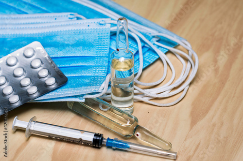 a syringe tablets in blisters medical hygiene masks and ampoules with medicines on the table