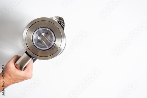 silver metal teapot in hand on white background. Copy space, top view, flat lay