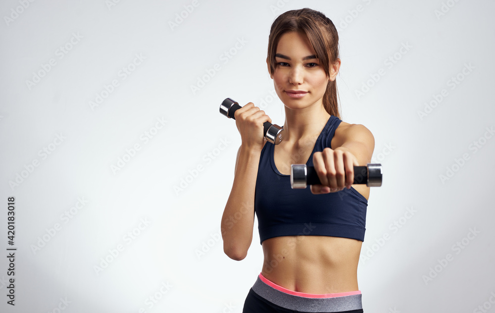 sportswoman with dumbbells on a light background gesturing with her hands fitness model sportswoman with dumbbells on a light background gesturing with her hands fitness model