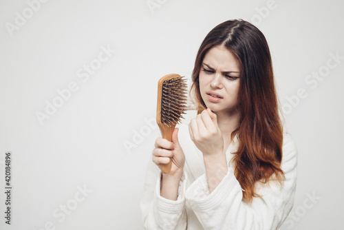 hair loss health problems woman with a comb in her hand on a light background