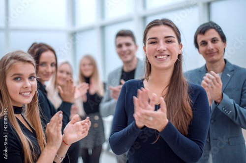 group of happy employees standing in the office applauding