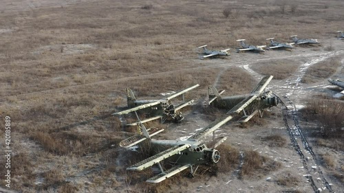 Three Broken transport planes An-2 - Colt - light transport aircrafts, biplanes on the airfield. Many planes at the military field airfield of abandoned military base. Aerial drone orbit shot.