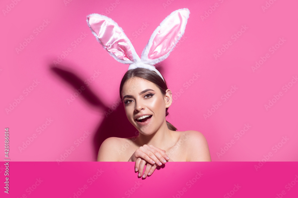 Easter bunny woman with rabbit ears. Beautiful young girl with on pink blank poster. Easter bunny woman with rabbit ears. Beautiful young girl with on pink blank poster.